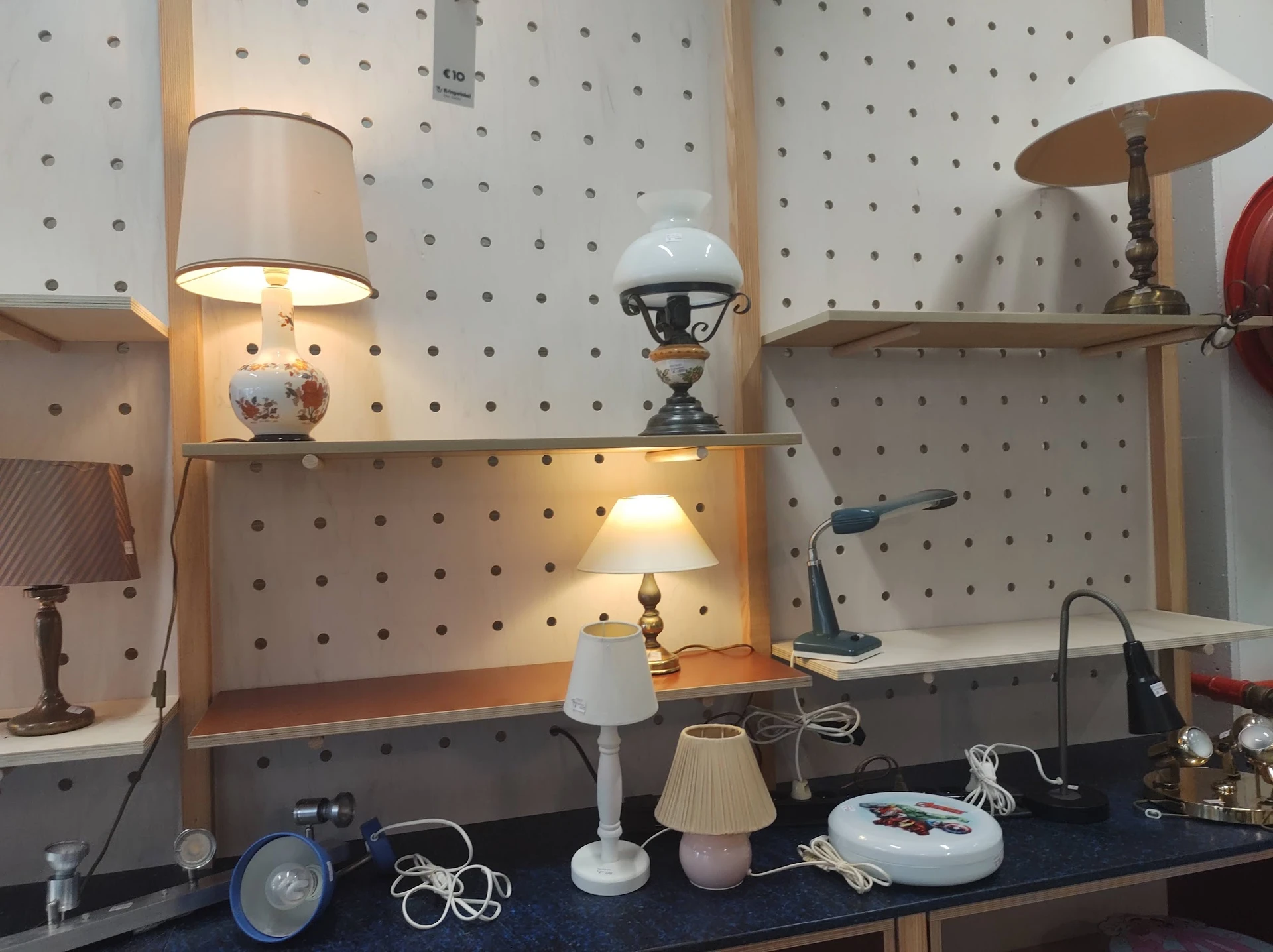 Uitgestalde lampen en verlichting op pegboard en toonbank in kringloopwinkel