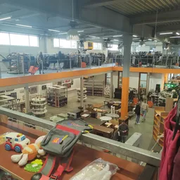 Overzicht van kringloopwinkel met twee verdiepingen, stellingen met spullen en speelgoed op voorgrond