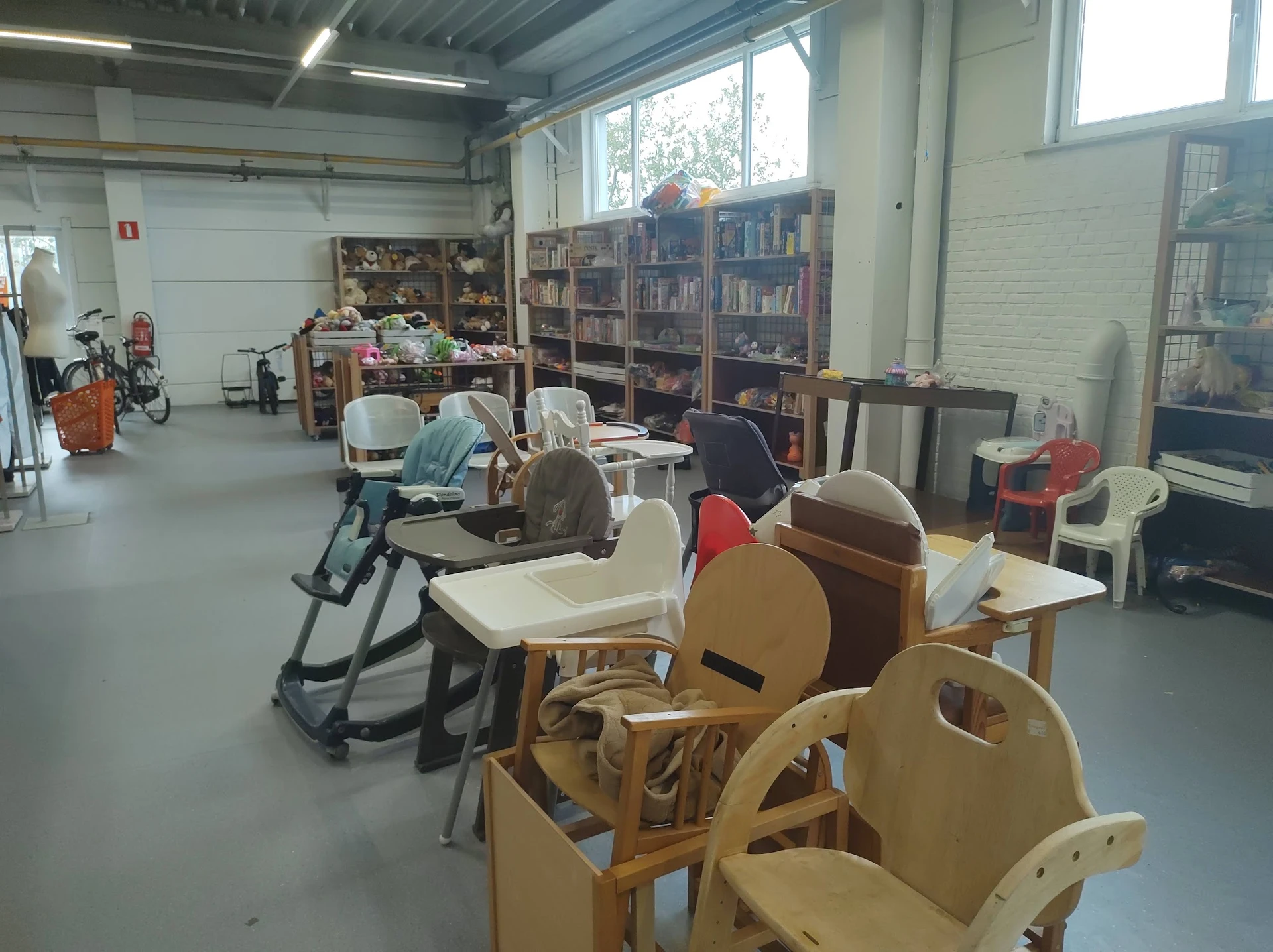 Winkelruimte met houten stoelen, fietsen, boekenkasten en diverse tweedehands spullen