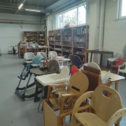 Winkelruimte met houten stoelen, fietsen, boekenkasten en diverse tweedehands spullen
