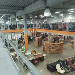 Overzicht van kringloopwinkel met twee verdiepingen, oranje balkons, stellingen met kleding en diversen spullen