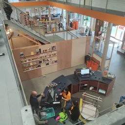 Overzicht van de winkelruimte met balie, houten stellingen met spullen en trap naar bovenverdieping