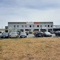 Voorgevel van kringloopwinkel aan Heistraat met parkeerplaats en geparkeerde auto's