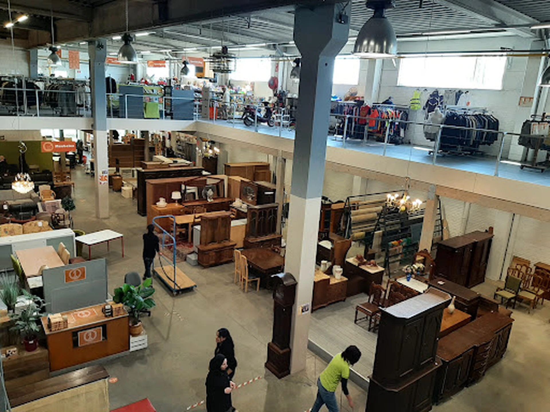 Ruim interieur van kringloopwinkel met meubels, kasten en huisraad uitgestald op de vloer en tegen de wanden