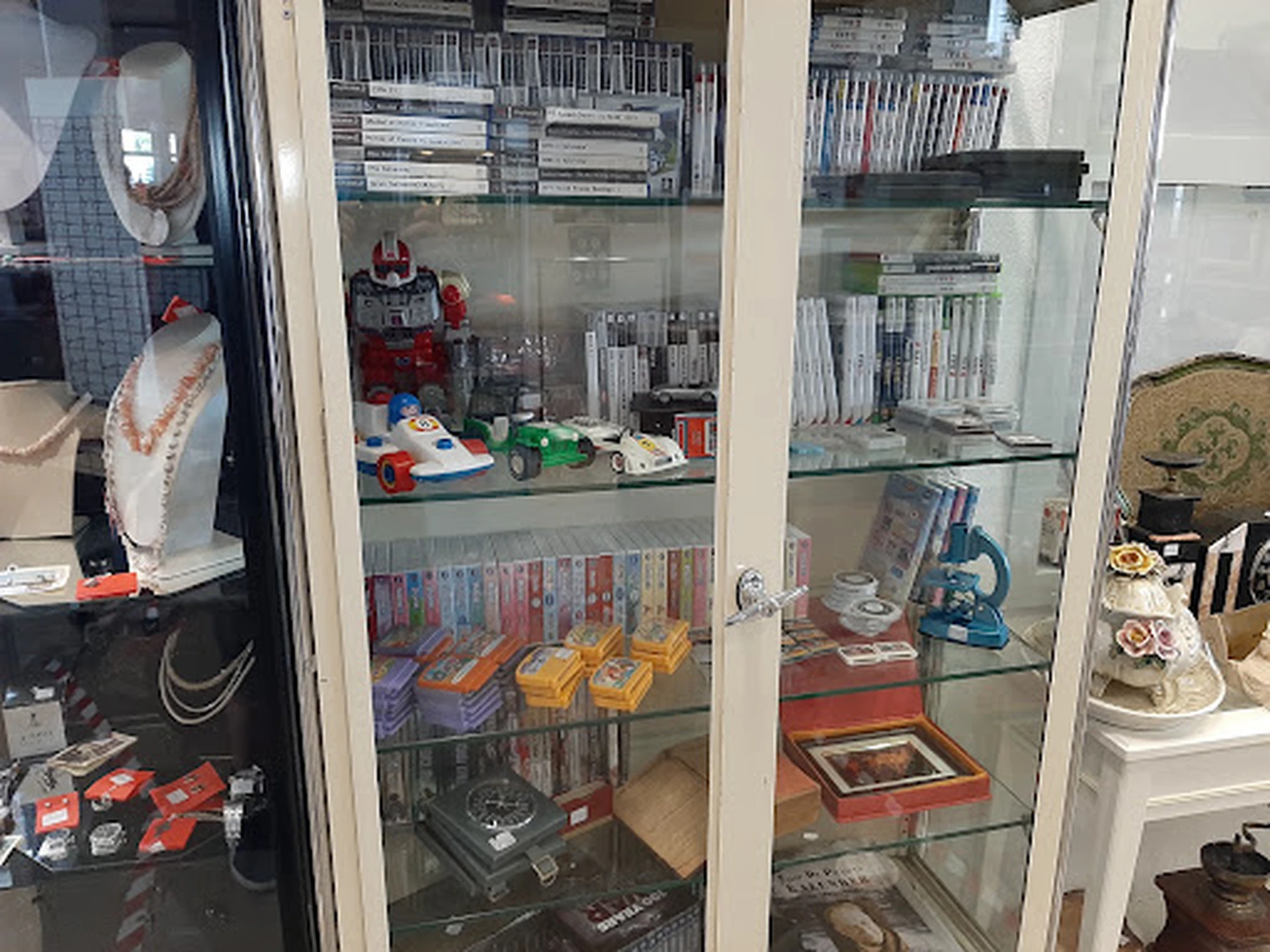 Glazen vitrinekasten met tweedehands verzamelaars items, speelgoed, dvd's en boeken