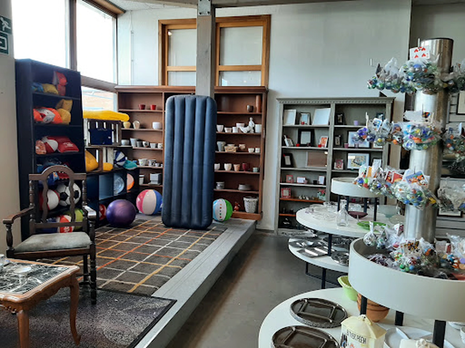Winkelvloer met stellingen, boeken, speelgoed, bloemen en decoratieve items in een kringloopwinkel