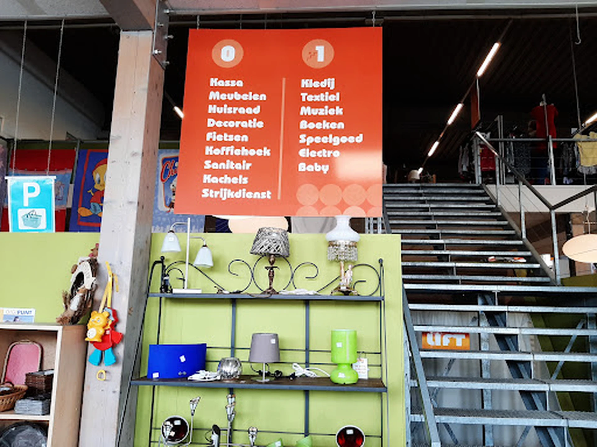 Winkelinterieur met groene stellage vol huishoudelijke artikelen en trap op achtergrond