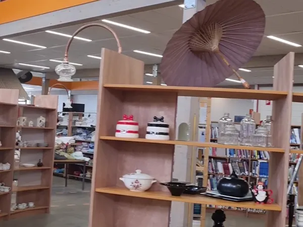 Winkelinterieur met houten stellingen vol huishoudartikelen, decoratie en boeken