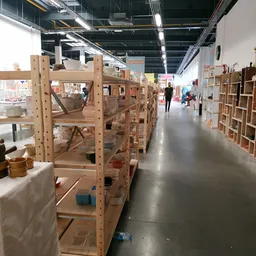 Winkelgang met houten stellingen en kasten vol tweedehands spullen in een ruime hal