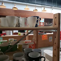 Houten stellingkast met diverse servies, kopjes en huishoudartikelen op meerdere niveaus