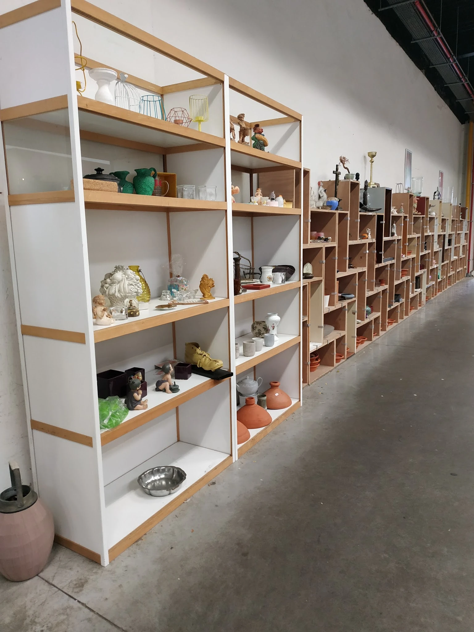 Houten stellingen met diverse huishoudelijke artikelen, servies, decoratie en gebruiksvoorwerpen uitgestald