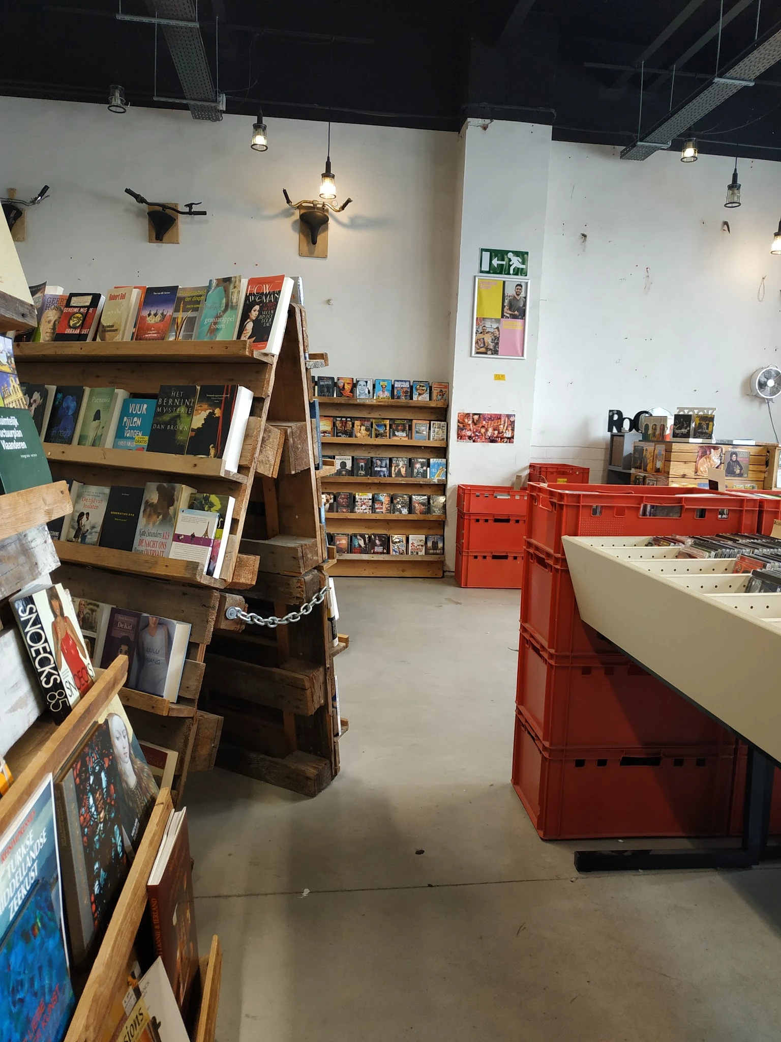 Winkelinterieur met houten boekenrekken, rode kratten en vitrinekast met tweedehands artikelen