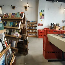 Winkelinterieur met houten boekenrekken, rode kratten en vitrinekast met tweedehands artikelen