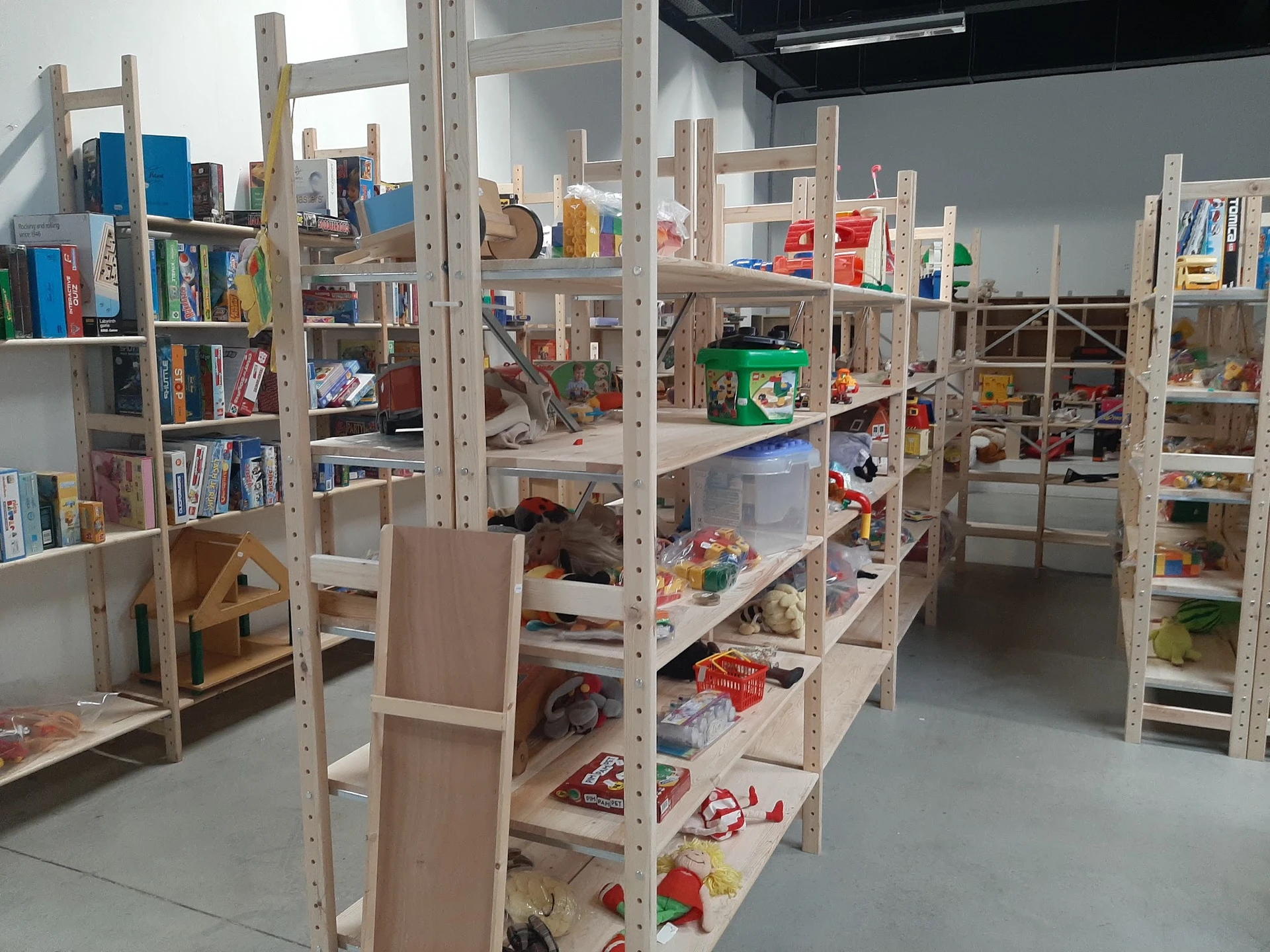 Houten stellingen met boeken, speelgoed en diverse tweedehandsartikelen in kringloopwinkel