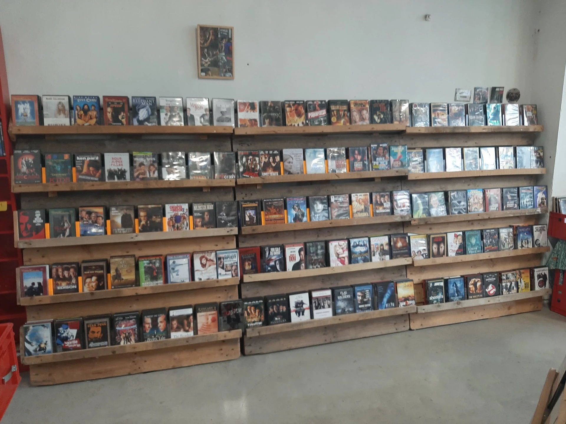 Houten wandrekken vol met dvd's, blu-rays en andere media in het assortiment van de winkel
