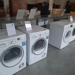 Vitrinekast met verschillende witte wasmachines en drogers met prijskaartjes
