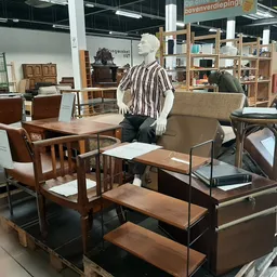 Uitgestalde meubels in de winkel: houten stoelen, tafels, fauteuils en kasten