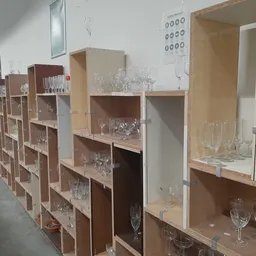 Houten stellingen met glazen bekers en drinkglazen uitgestald in verschillende vakken