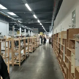 Winkelinterieur met houten stellingen en kasten vol spullen, bezoekers lopen tussen de gangen door