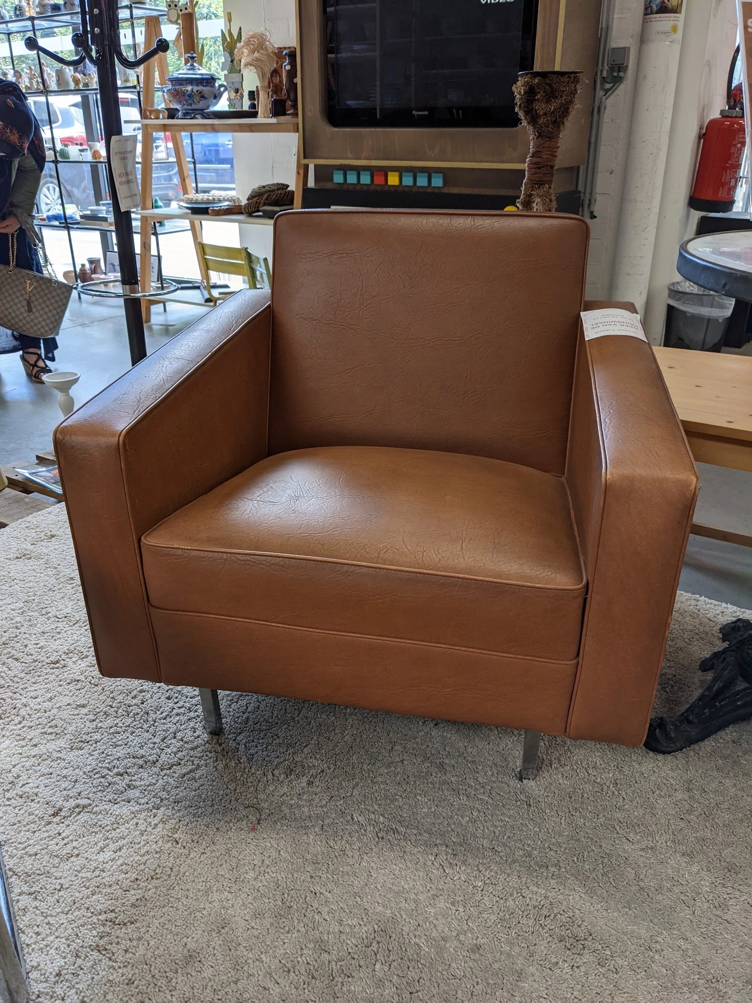 Bruinleren fauteuil met armleuningen op grijze poten