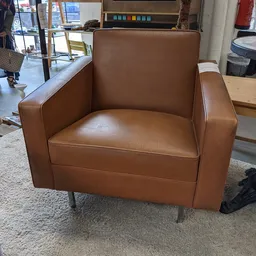 Bruinleren fauteuil met armleuningen op grijze poten