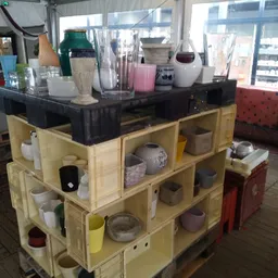 Houten stellingkast met verschillende huishoudartikelen, vazen, bekers en decoratieve voorwerpen uitgestald