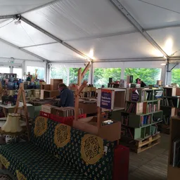 Ruim verlicht interieur van kringloopwinkel met boekenrekken, meubels en diverse spullen, groene vloer met patroon
