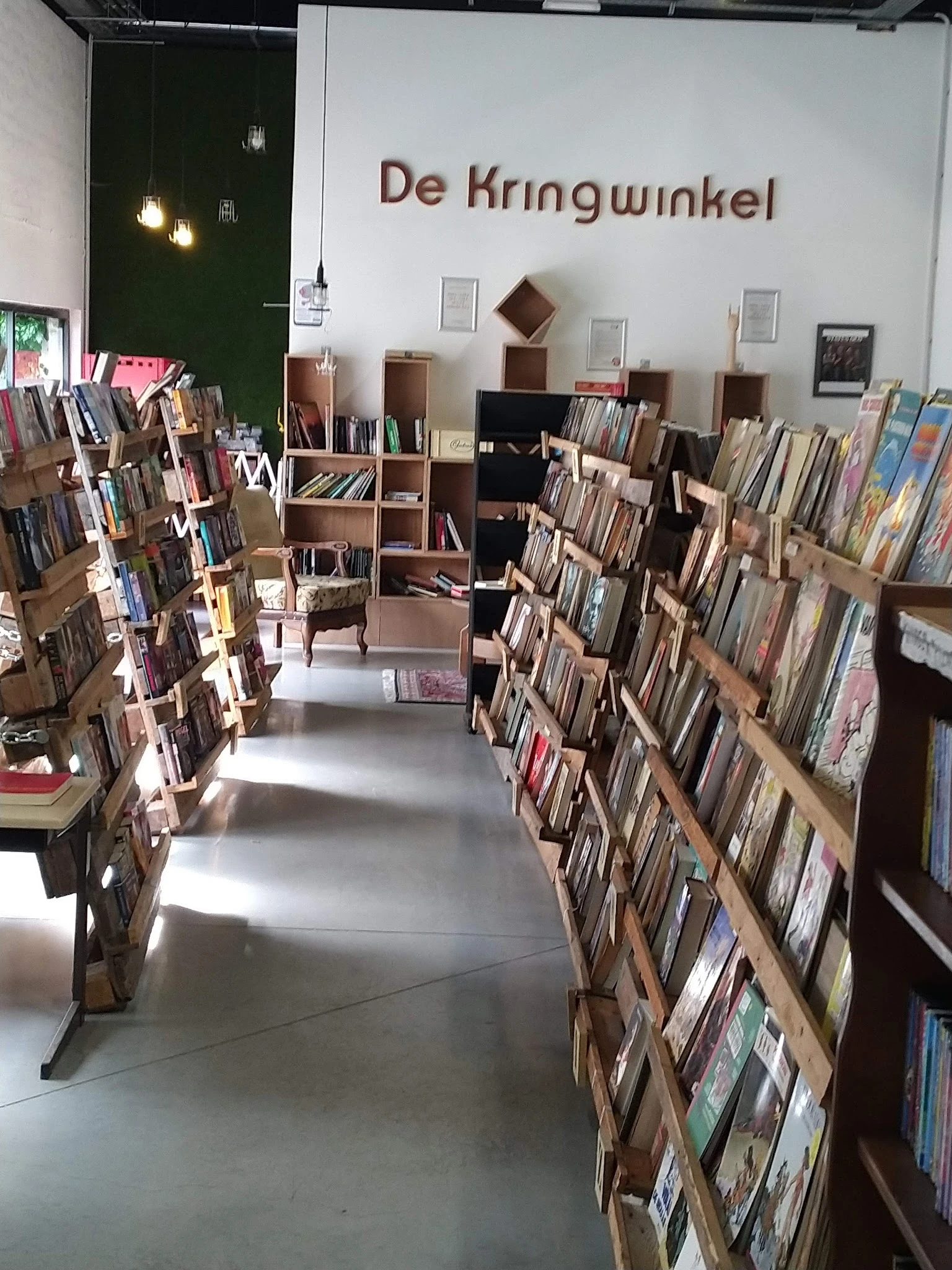 Winkelinterieur met houten stellingen vol cd's en dvd's langs beide zijden van het gangpad