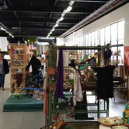 Winkelvloer van kringloopwinkel met diverse uitgestalde spullen, meubels, kleding en decoratie in verschillende standsecties