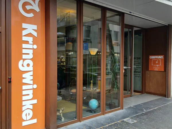 Winkelvoorgevel met groot oranje bord met witte letters en glazen deuren