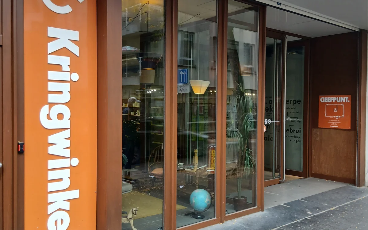 Winkelvoorgevel met groot oranje bord met witte letters en glazen deuren