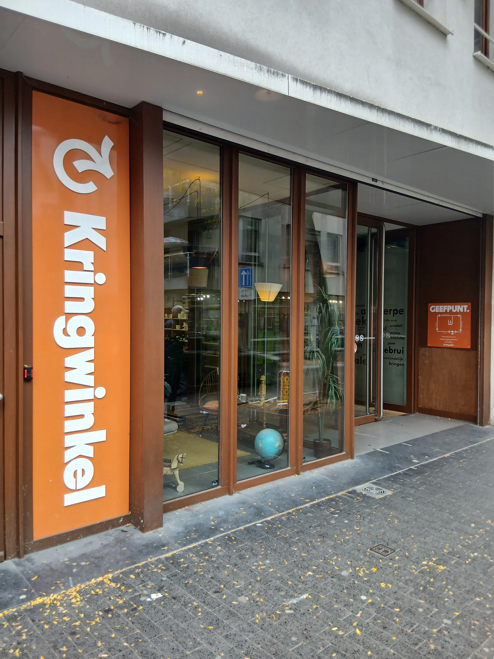 Winkelvoorgevel met groot oranje bord met witte letters en glazen deuren