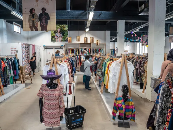 Ruime winkelhal met kledingrekken, mannequins in kleding en bezoekers die rondlopen tussen het aanbod