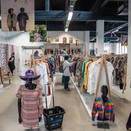 Ruime winkelhal met kledingrekken, mannequins in kleding en bezoekers die rondlopen tussen het aanbod