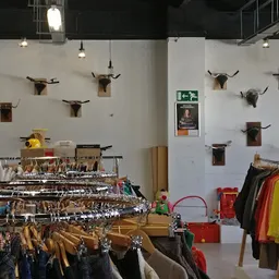 Winkelvloer met kledingrekken en decoratieve dierenkoppen aan de muur