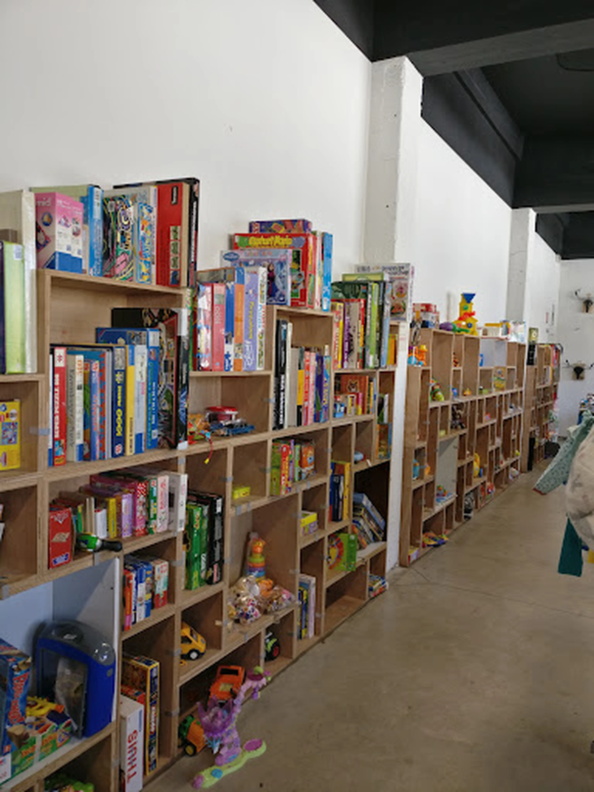 Houten stellingen met uitgestalde spellen, boeken en speelgoed in een kringloopwinkel