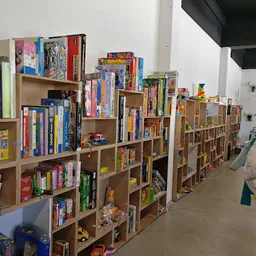 Houten stellingen met uitgestalde spellen, boeken en speelgoed in een kringloopwinkel