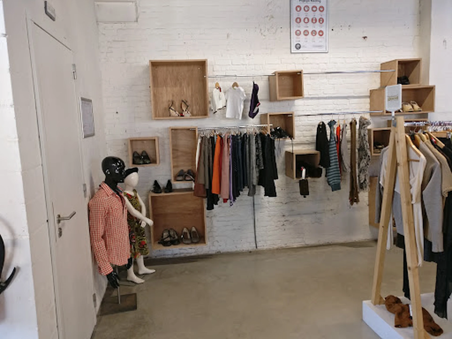 Winkelvloer van kringloopwinkel met houten stellingen, uitgestalde kleding op hangers en kledingrekken