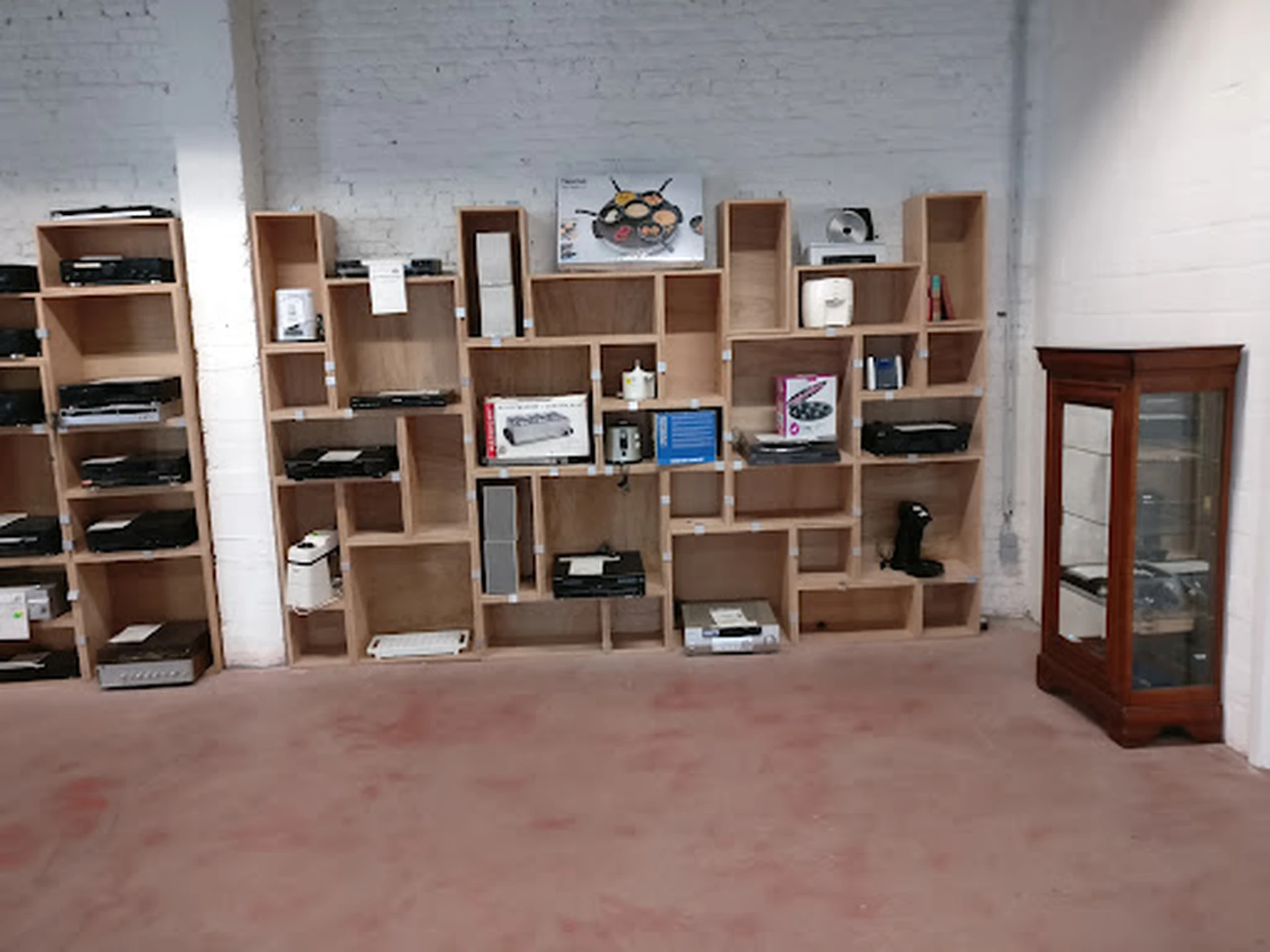 Winkelvloer met houten wandstellingen vol met boeken, huishoudartikelen en elektronische apparatuur