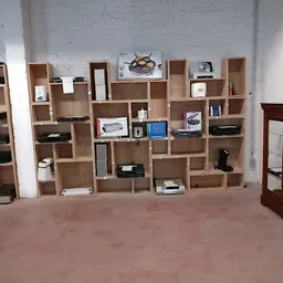 Winkelvloer met houten wandstellingen vol met boeken, huishoudartikelen en elektronische apparatuur