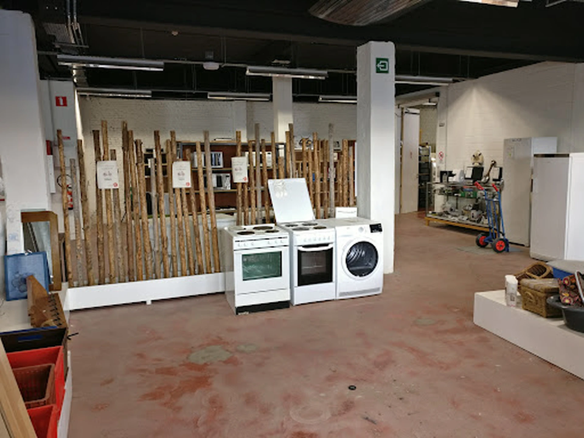 Winkelvloer met uitgestalde huishoudapparaten en houten pallets in een kringloopwinkel