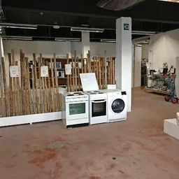 Winkelvloer met uitgestalde huishoudapparaten en houten pallets in een kringloopwinkel