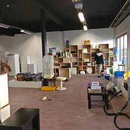 Winkelvloer met stellingen vol houten dozen en spullen, geel en blauw plastic bakken op de grond