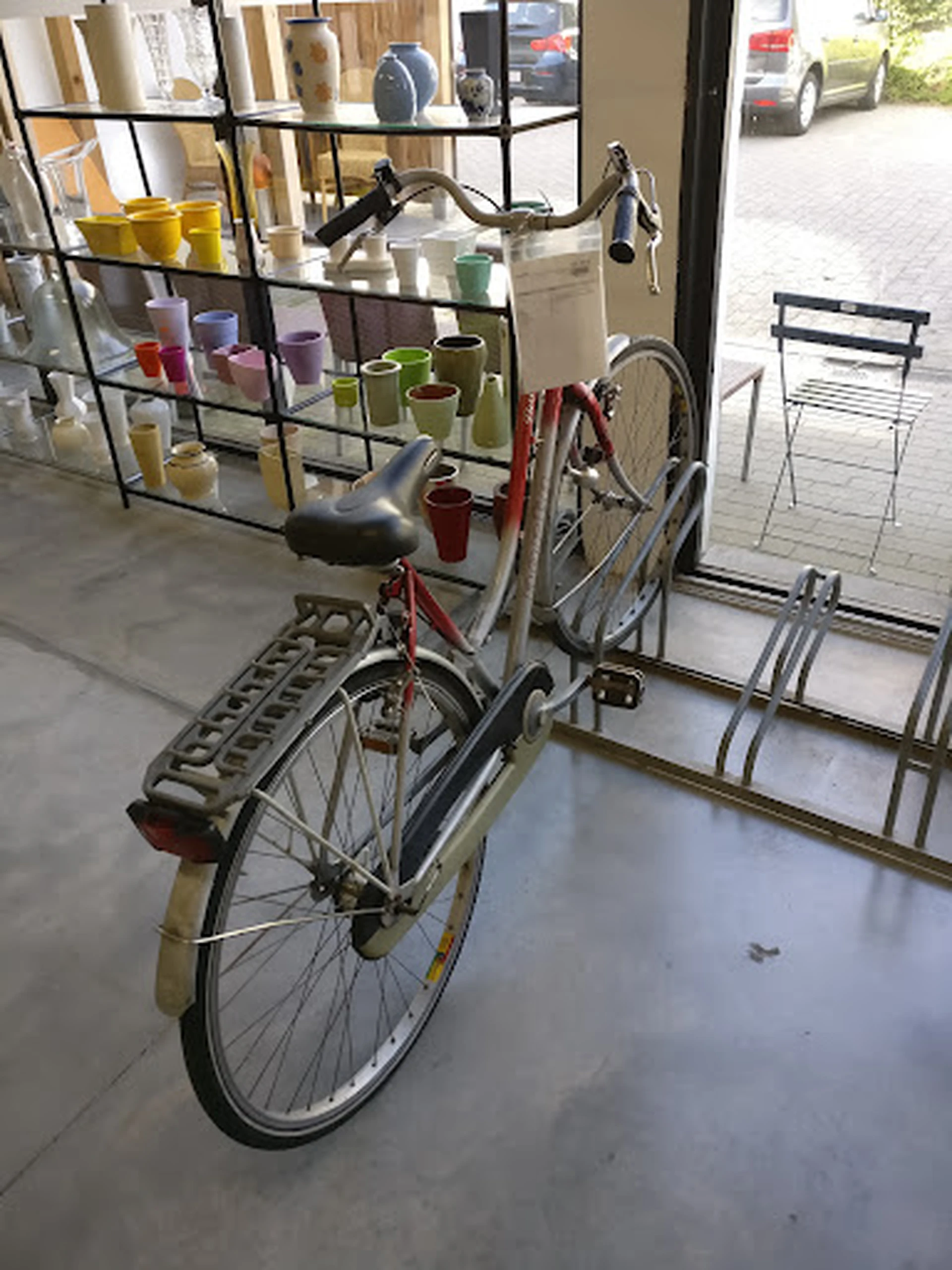 Tweedehands fiets met mand en diverse huishoudelijke artikelen in een kringloopwinkel
