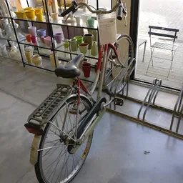 Tweedehands fiets met mand en diverse huishoudelijke artikelen in een kringloopwinkel