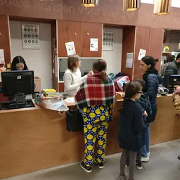 Bezoekers aan de balie van een kringloopwinkel, personeel helpt klanten