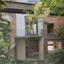 Bakstenen gevel van gebouw met balkon, veel begroeid met klimop en bladeren