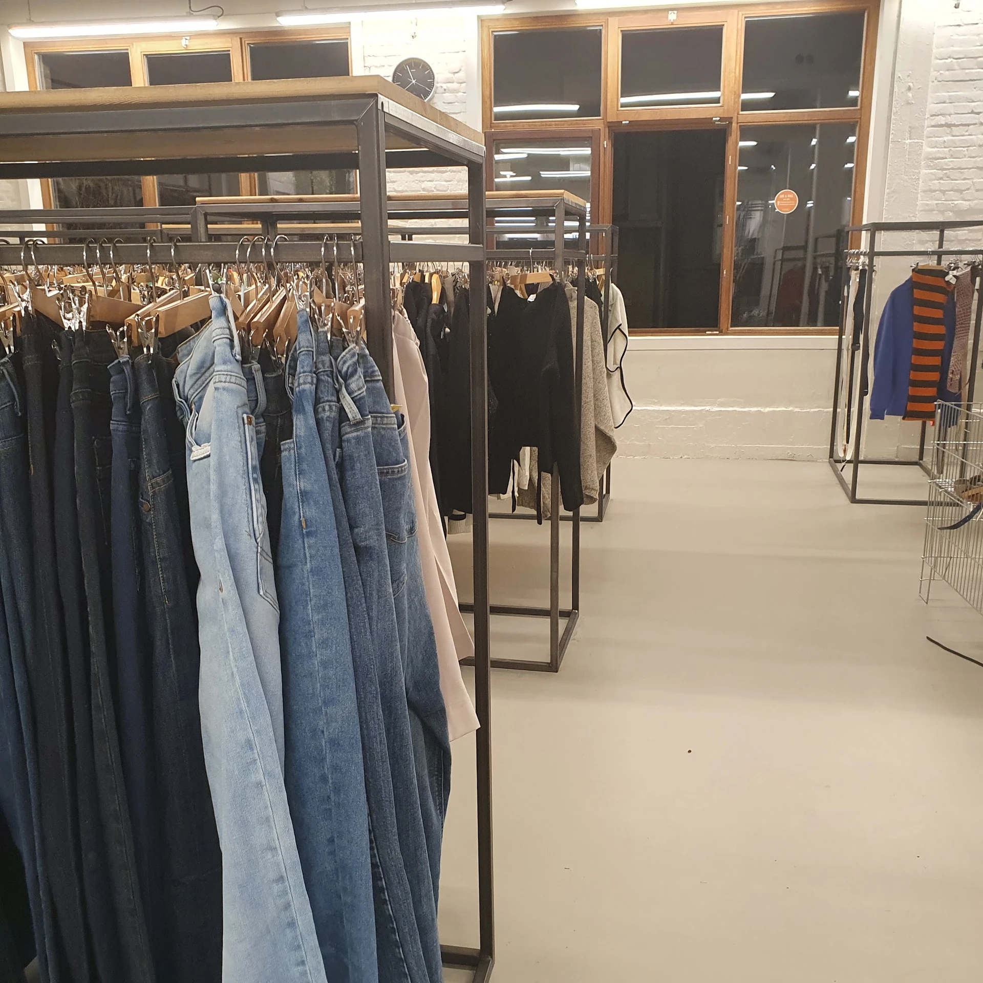 Rekken met tweedehands kleding, vooral jassen en jeans op hangers in de winkel