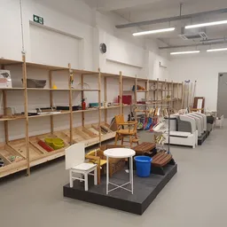 Overzicht van de winkelruimte met houten stellingen vol spullen en diverse meubelstukken op de grond
