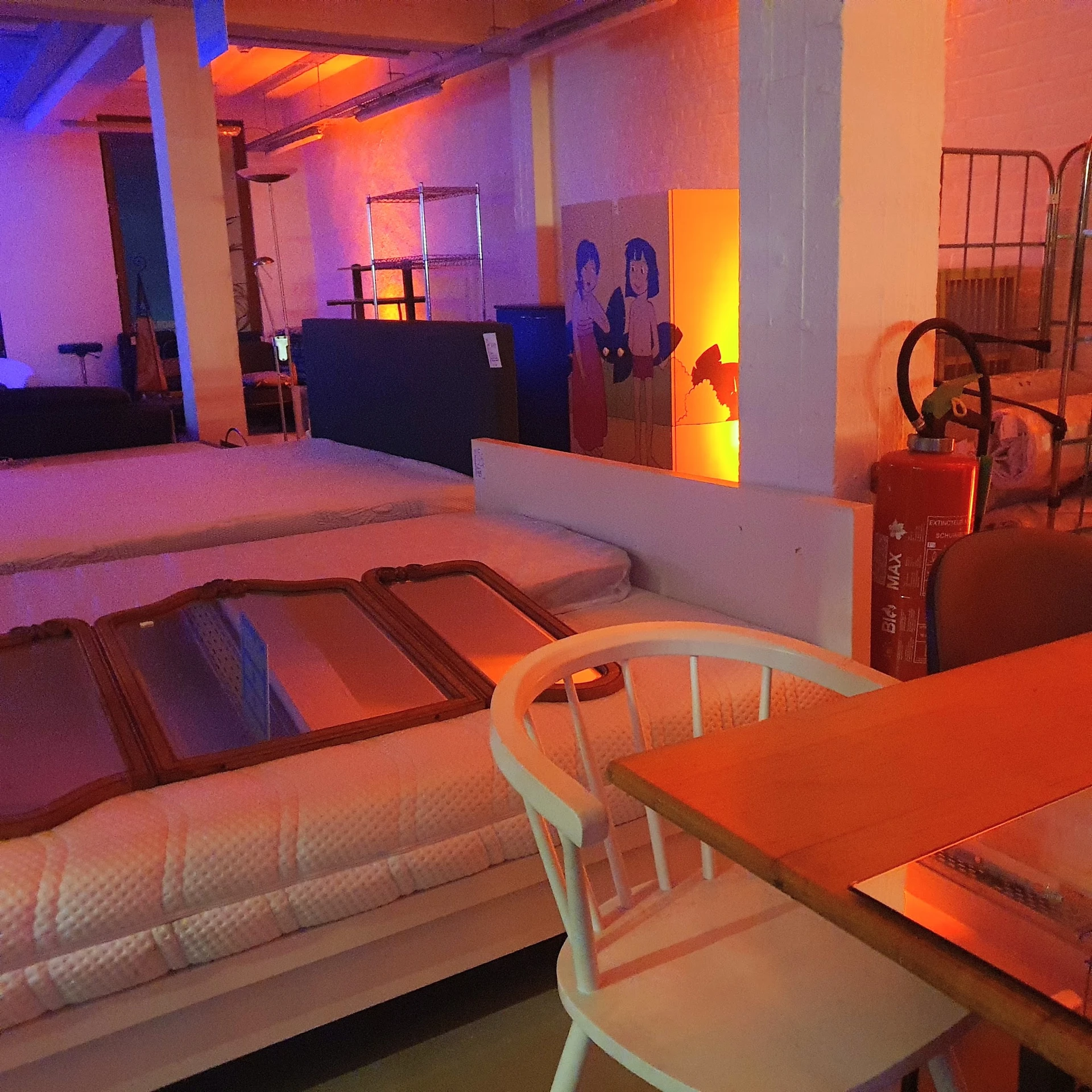 Winkelinterieur met bedden, tafels en stoelen onder paars en oranje verlichting